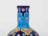 un vase bleu avec un motif sur une surface blanche