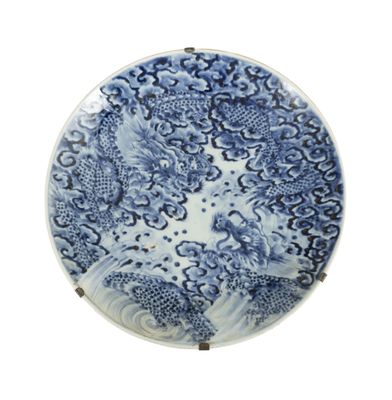 assiette bleue et blanche ornée d'un motif de dragon sur fond blanc