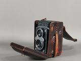 un étui en cuir marron auquel est attaché un appareil photo