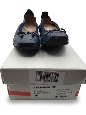 une paire de chaussures pour femme dans une boîte posée sur une surface blanche
