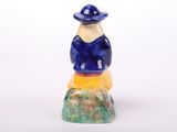a figurine of a man sitting on a rock wearing a hat