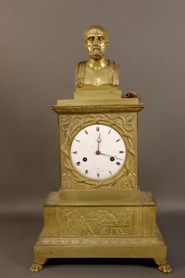 une horloge en or surmontée d'un buste d'homme