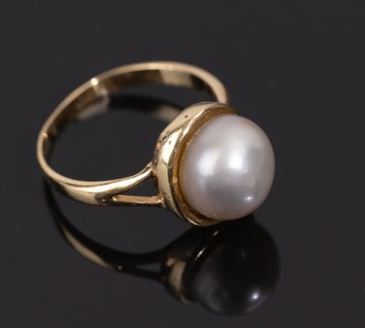 a gold ring with a white pearl on a black surface