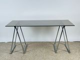 une photo d'une table en verre avec des pieds en métal posée sur un sol recouvert de moquette