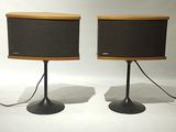 pair of speakers on stands with wires attached to them on a white surface