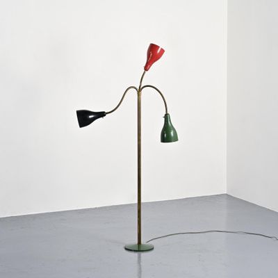 a red, green and black floor lamp in a corner of a room