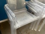 plusieurs chaises en plastique transparent empilées les unes sur les autres dans une pièce