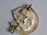 a silver pin with a plane on it on a white surface