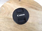 a black camera lens cap on a wooden table
