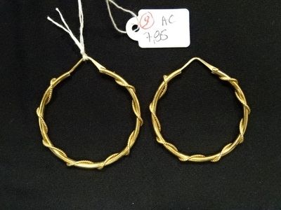 deux paires de boucles d'oreilles créoles en or avec un fil torsadé sur fond noir