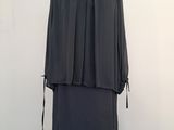 black dress on a mannequin stand in front of a white wall