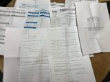 a lot of papers on a table with a calculator in the background