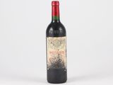 an old bottle of red wine sitting on top of a white table