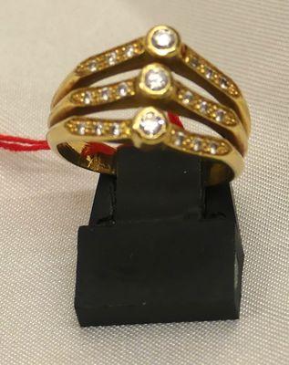a gold ring with diamonds on it on a black stand