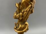 a gold statue of a bird sitting on a tree branch