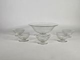quatre bols en verre transparent et un bol posé sur une surface blanche
