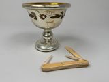 a small silver cup with a wooden spoon next to it