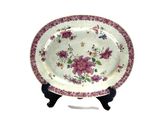 a white plate with pink flowers on it on a stand