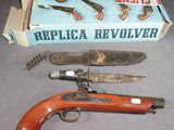 une boîte contenant un pistolet, un couteau et d'autres objets, posée sur la table