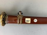 a brown pipe with a brass handle on a white surface
