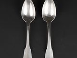 pair of silver spoons on a black surface with a black background