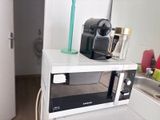 un micro-ondes sur lequel est posée une tasse, dans une cuisine