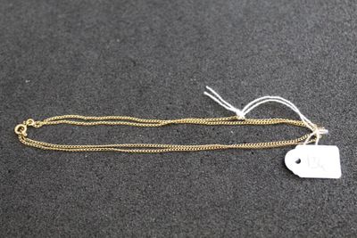 une chaîne en or à laquelle est accrochée une médaille, posée sur une surface noire