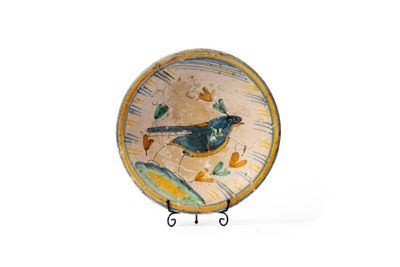 une assiette sur laquelle est peint un oiseau, posée sur un socle