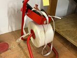 un distributeur de papier toilette posé par terre à côté d'une paire de chaussures