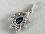 a close up of a silver pendant with a blue stone