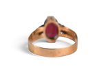 a close up of a gold ring with a red stone