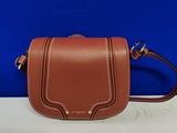 un sac à bandoulière en cuir marron posé sur une table blanche