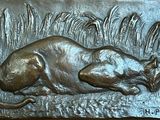 a bronze plaque of a cat laying in the grass