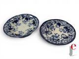 two blue and white plates with birds on them on a white surface