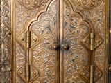 an ornate wooden door with a metal handle in a room