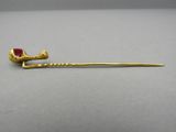 a close up of a gold stick with a red stone on it
