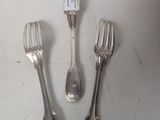 three forks and spoons sitting on top of a white table