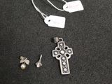 a silver cross and a pair of earrings on a table