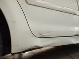 a close up of a white car with a denting on it