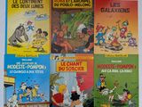 Plusieurs albums de BD sont alignés sur une surface blanche