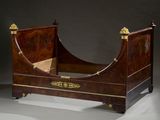 a bed that has a wooden frame with gold decorations on it