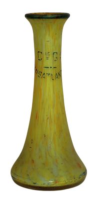 un vase jaune orné d'une inscription noire, posé sur une surface blanche