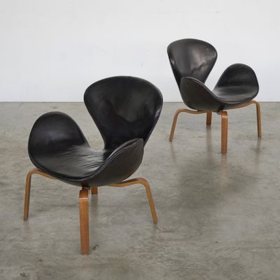 deux fauteuils en cuir noir aux pieds en bois dans une pièce blanche