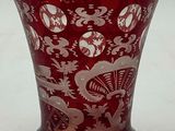 a red vase with white designs on it sitting on a table