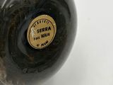 a black vase that has a brown label on it
