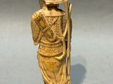 statue d'un homme portant un chapeau et une canne, posée sur un socle en bois
