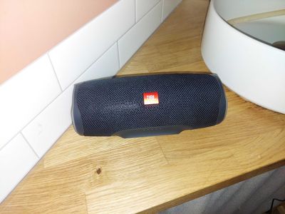 a black speaker sitting on a counter next to a mirror