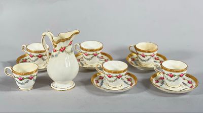 un pichet blanc et six tasses avec leurs soucoupes posés sur une table