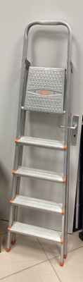 a ladder that is leaning against a wall next to a trash can
