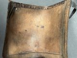 a person holding a brown leather bag with a handle